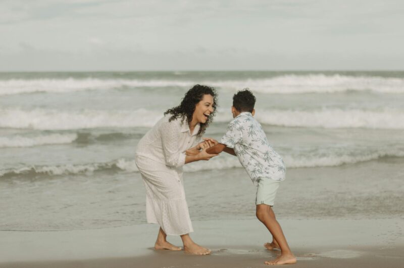 joyful mother and son playing on beach