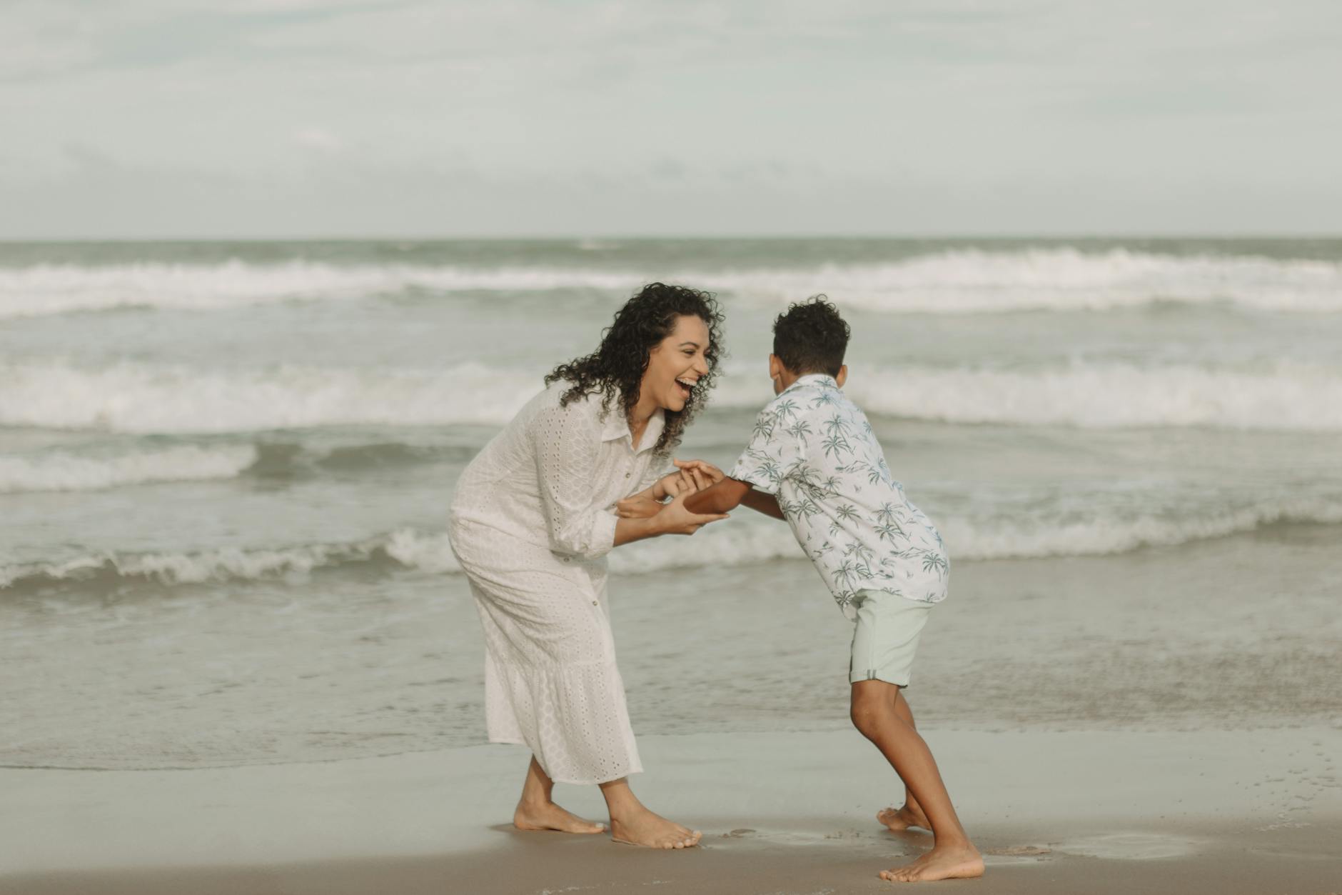 joyful mother and son playing on beach