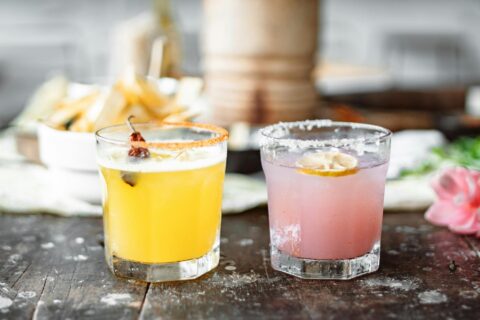 two clear drinking glasses with pink and yellow liquid